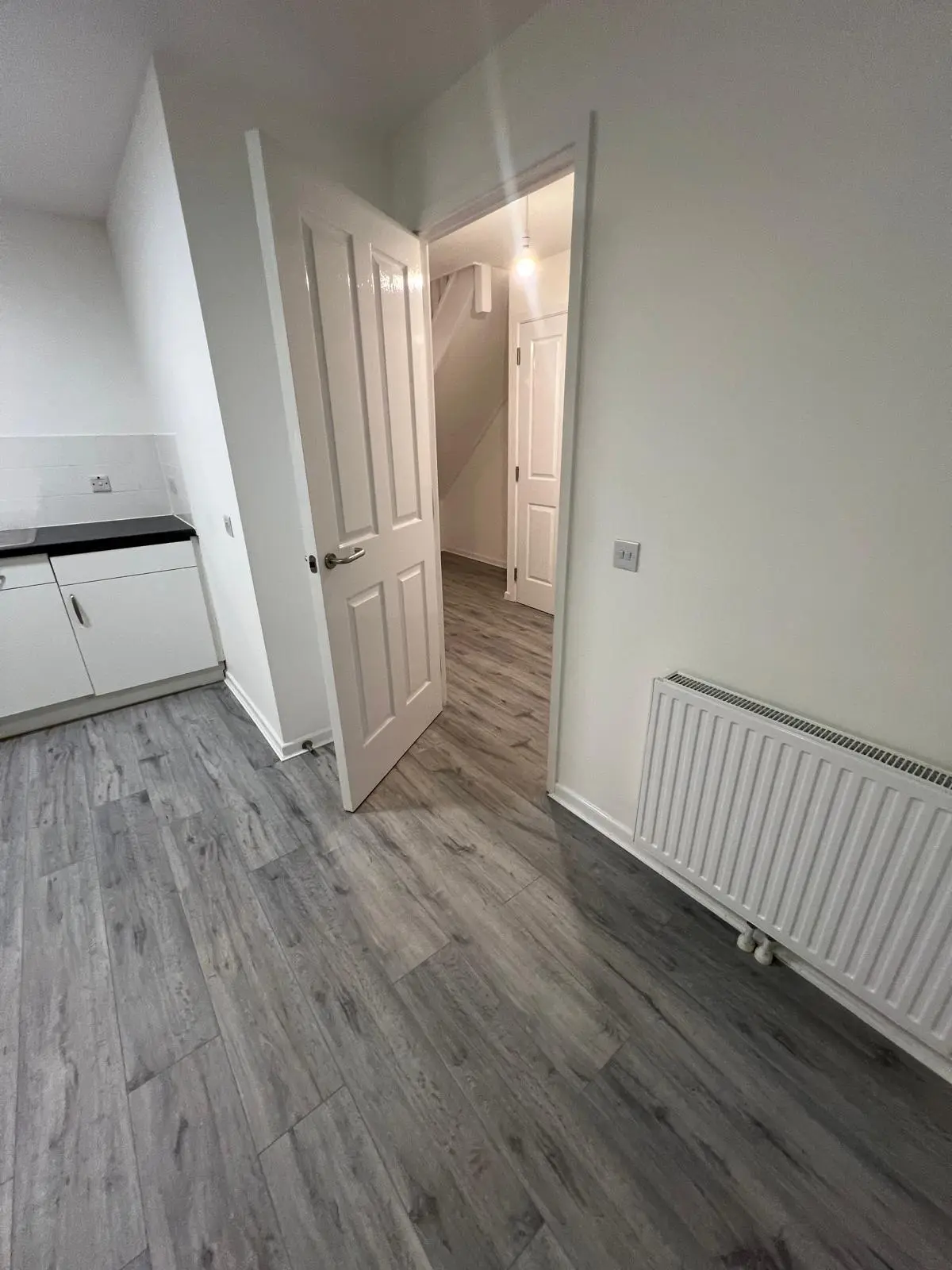 Grey wood-effect laminate flooring fitted through a kitchen and hallway